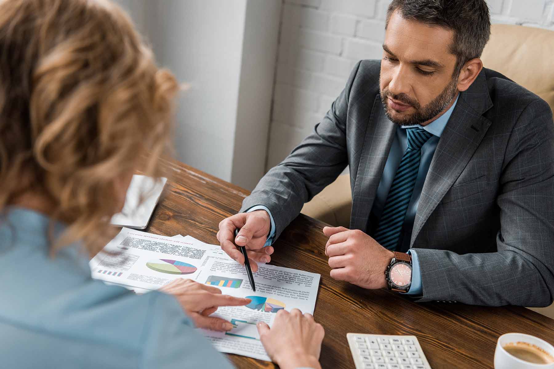 A consultant discussing graphs and charts with a client during a meeting A consultant discussing graphs and charts with a client during a meeting
