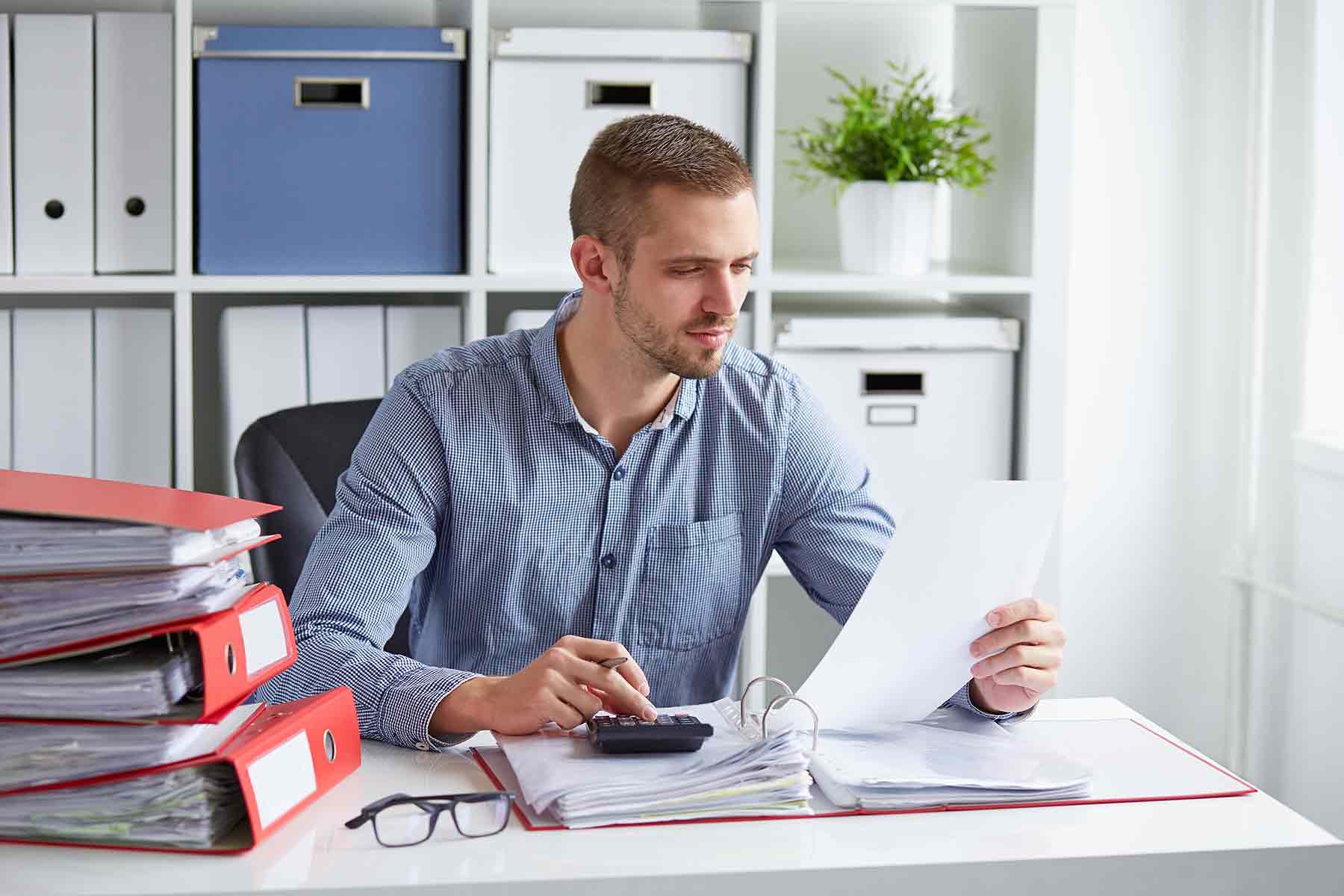 An accountant analyzing financial documents at his desk in the office